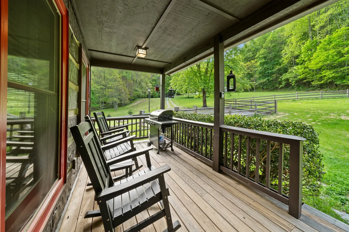 A fenced-in yard filled with lush greenery, featuring rocking chairs and a grill, providing a safe outdoor area for kids to play and for families to gather.