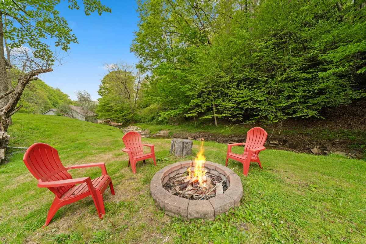 A cozy fire pit area with vibrant red chairs, set among lush greenery. This outdoor space invites couples to share stories, stargaze, or simply enjoy warmth under the night sky, away from distractions.